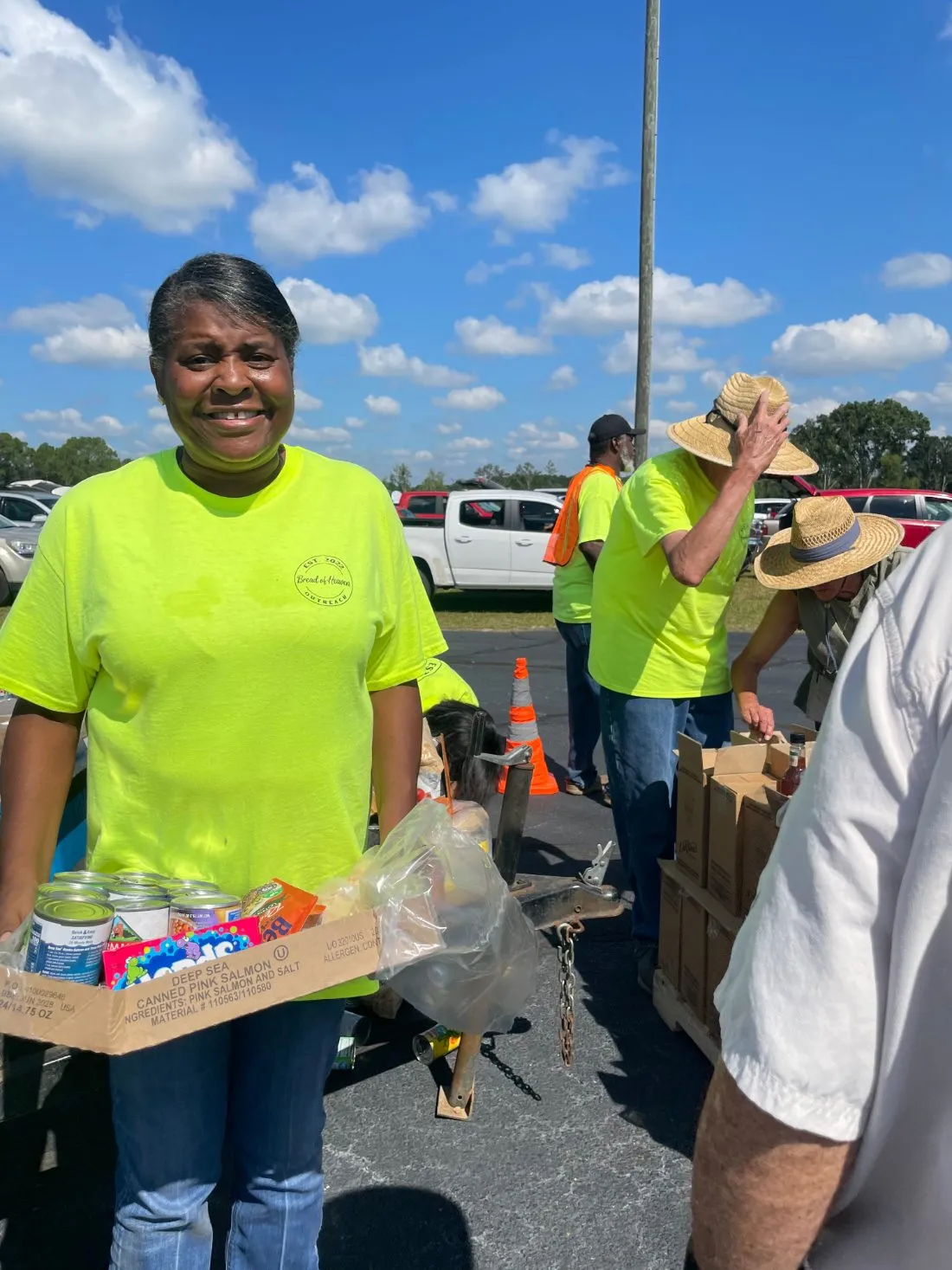 A smiling Bread of Heaven volunteer carrying a box of groceries
